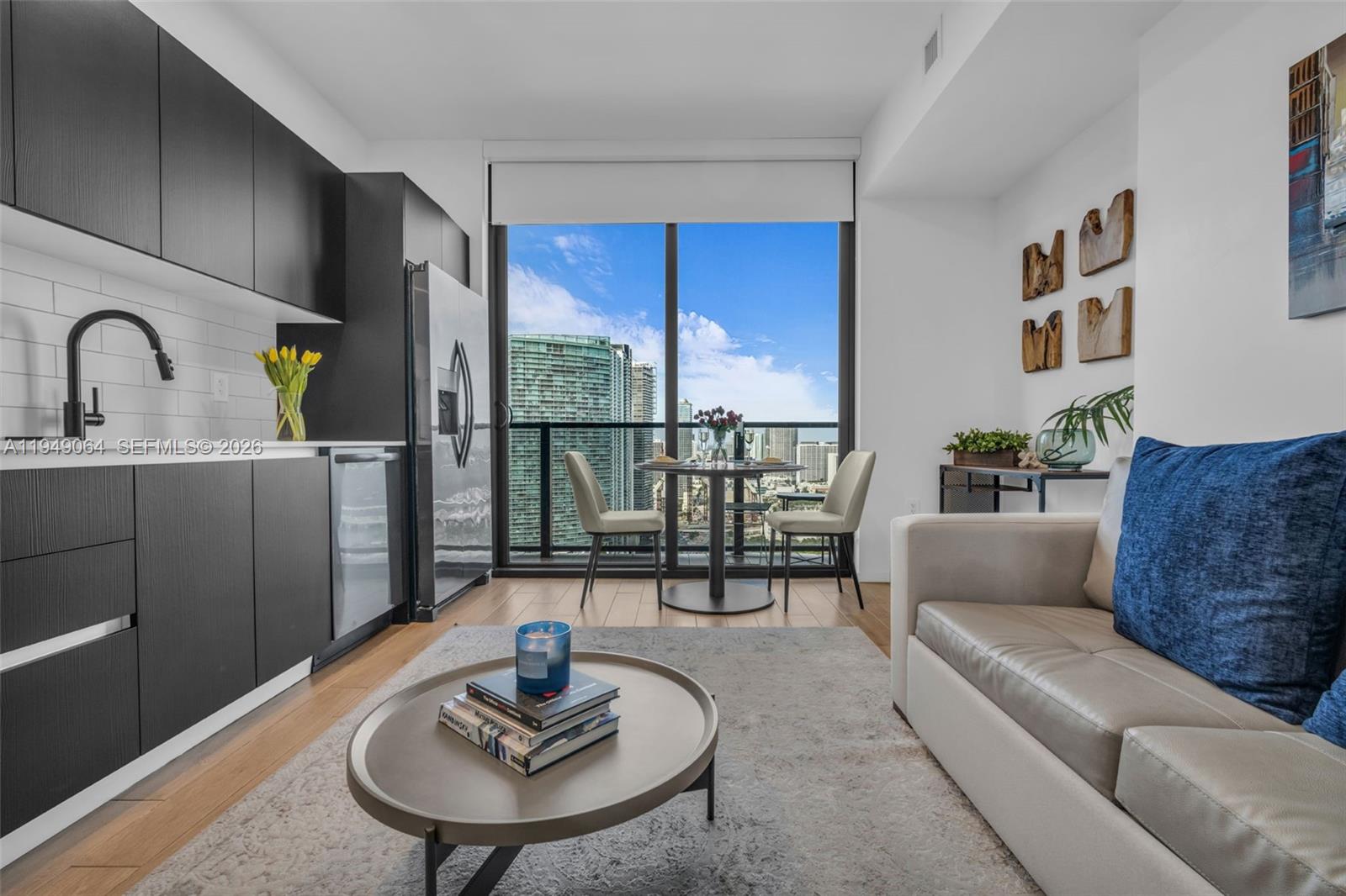 A modern apartment living area features a kitchen, dining space, and balcony with city views — 398 NE 5th St # 3207, Miami FL 33132, MIAMI, FL