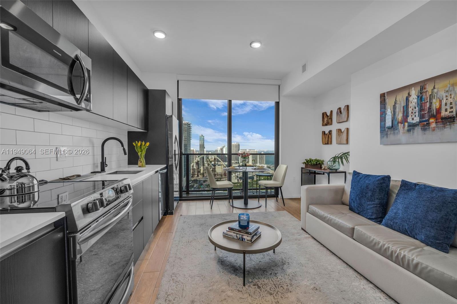 A modern studio apartment features a kitchen, living area, and floor-to-ceiling windows with city views — 398 NE 5th St # 3207, Miami FL 33132, MIAMI, FL