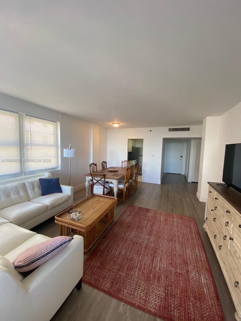 A living and dining area with white sofas, a wooden table, and a red rug — 100 Lincoln Rd # 721, Miami Beach FL 33139, MIAMI BEACH, FL
