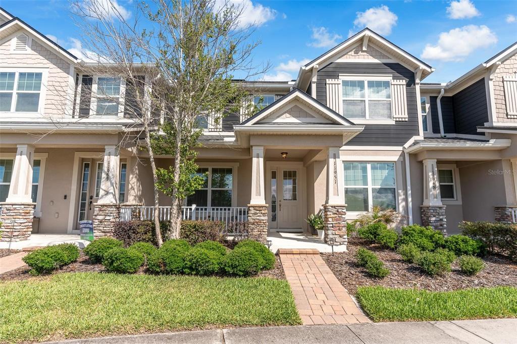 A two-story townhouse exterior features a stone-accented porch, a brick walkway, and dark siding — 11951 VERMILLION AVENUE, WINDERMERE, FL