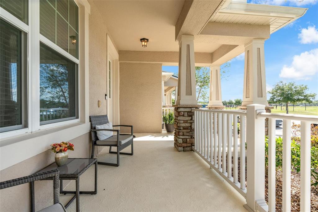 A covered porch features a stone-based column, white railing, and outdoor furniture — 11951 VERMILLION AVENUE, WINDERMERE, FL