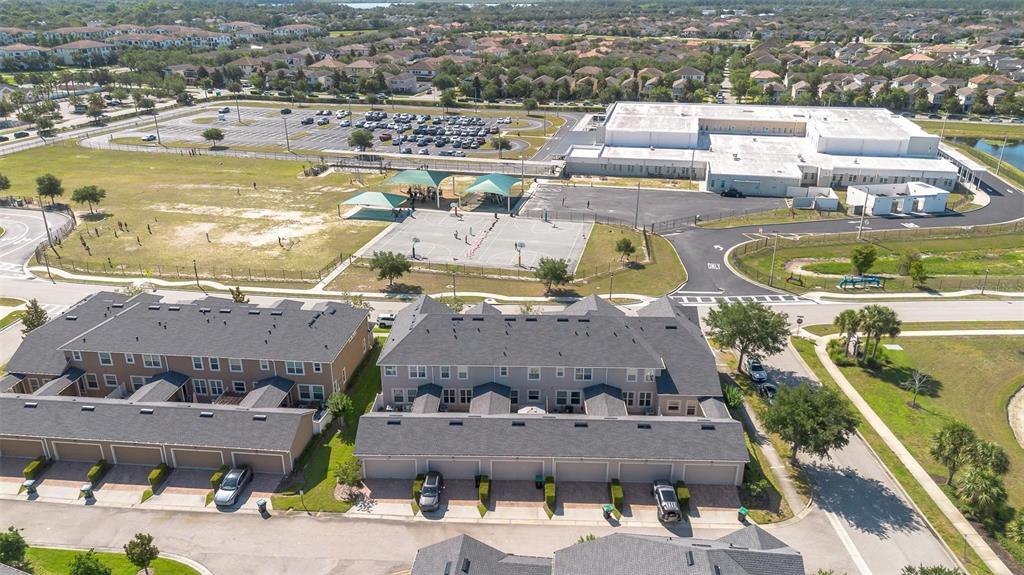An aerial view shows townhomes with garages adjacent to a school with a parking lot — 11951 VERMILLION AVENUE, WINDERMERE, FL