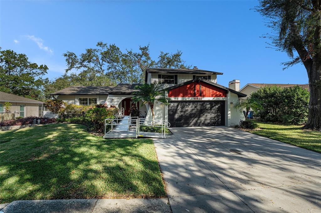 A two-story house with a red accent gable, a garage, and a metal wheelchair ramp — 4611 LANDSCAPE DRIVE, TAMPA, FL