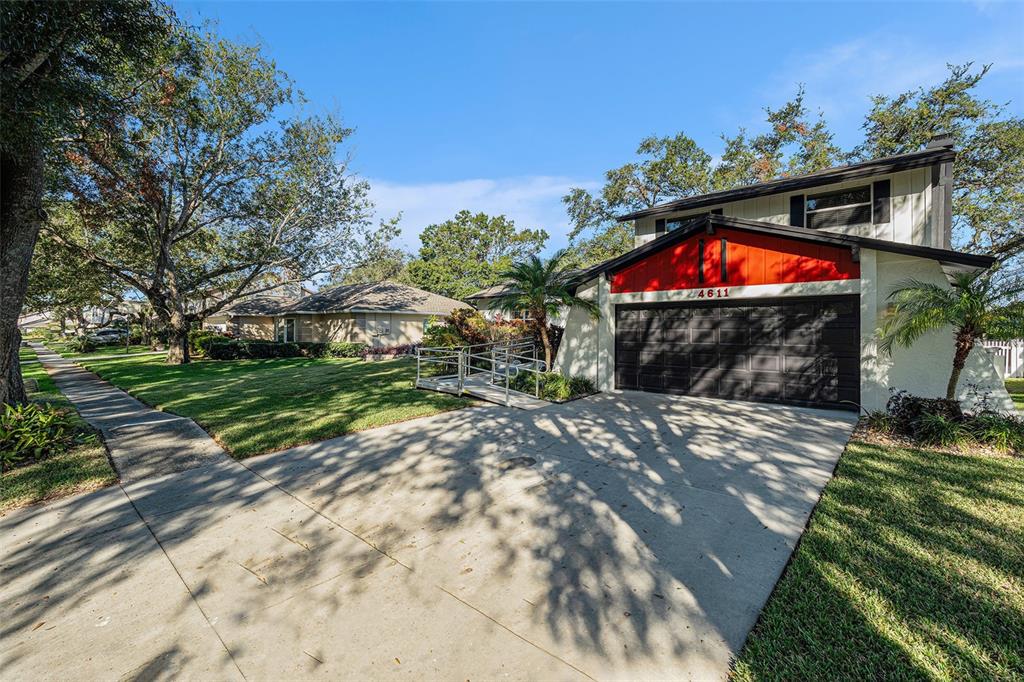 A two-story house with a red accent gable, a dark garage door, and a wheelchair ramp — 4611 LANDSCAPE DRIVE, TAMPA, FL