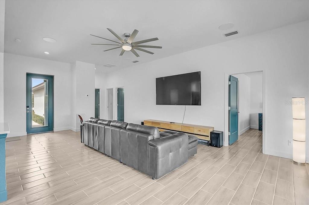 A living room features a grey sectional sofa, a wall-mounted television, and light-colored tile flooring — 112 HERCULES DRIVE, ROTONDA WEST, FL