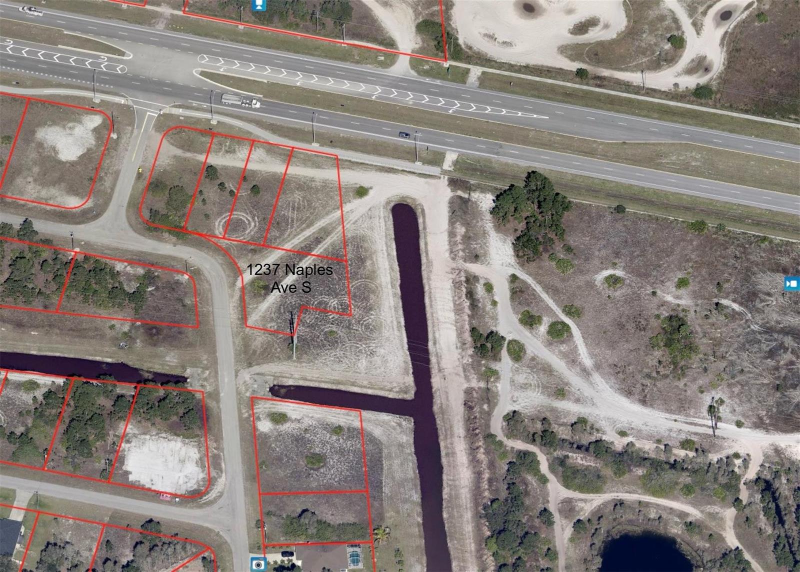 An aerial view shows a vacant lot outlined in red next to a drainage canal — 1237 Naples Avenue, Lehigh Acres FL 33913, LEHIGH ACRES, FL