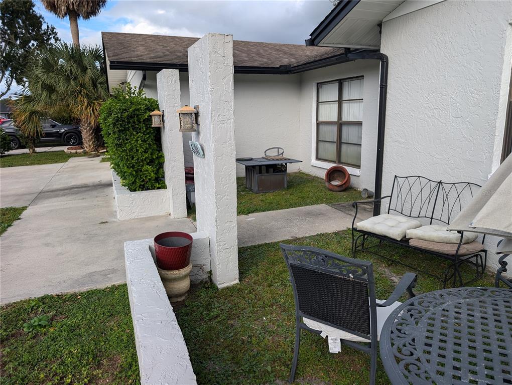A white stucco house exterior features a small patio area with metal furniture and landscaping — 4208 SUMMERDALE DRIVE, TAMPA, FL