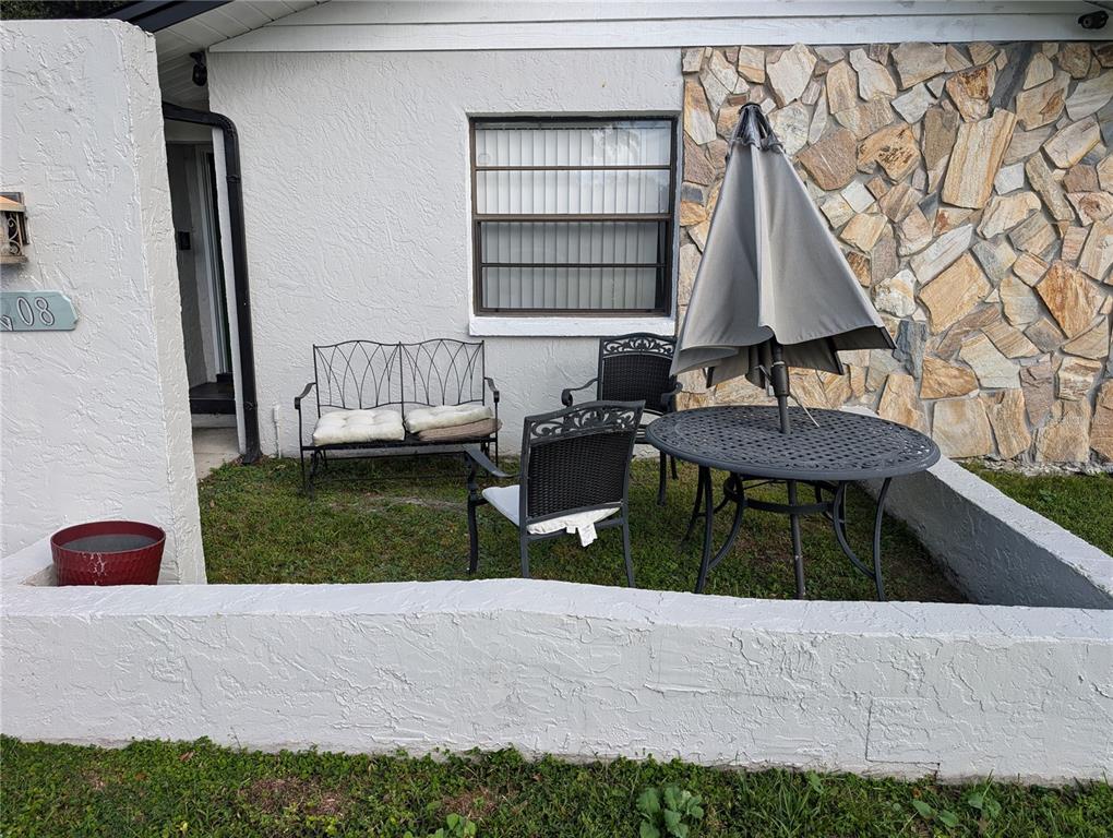 A patio area features a small table with an umbrella, chairs, and a metal bench — 4208 SUMMERDALE DRIVE, TAMPA, FL