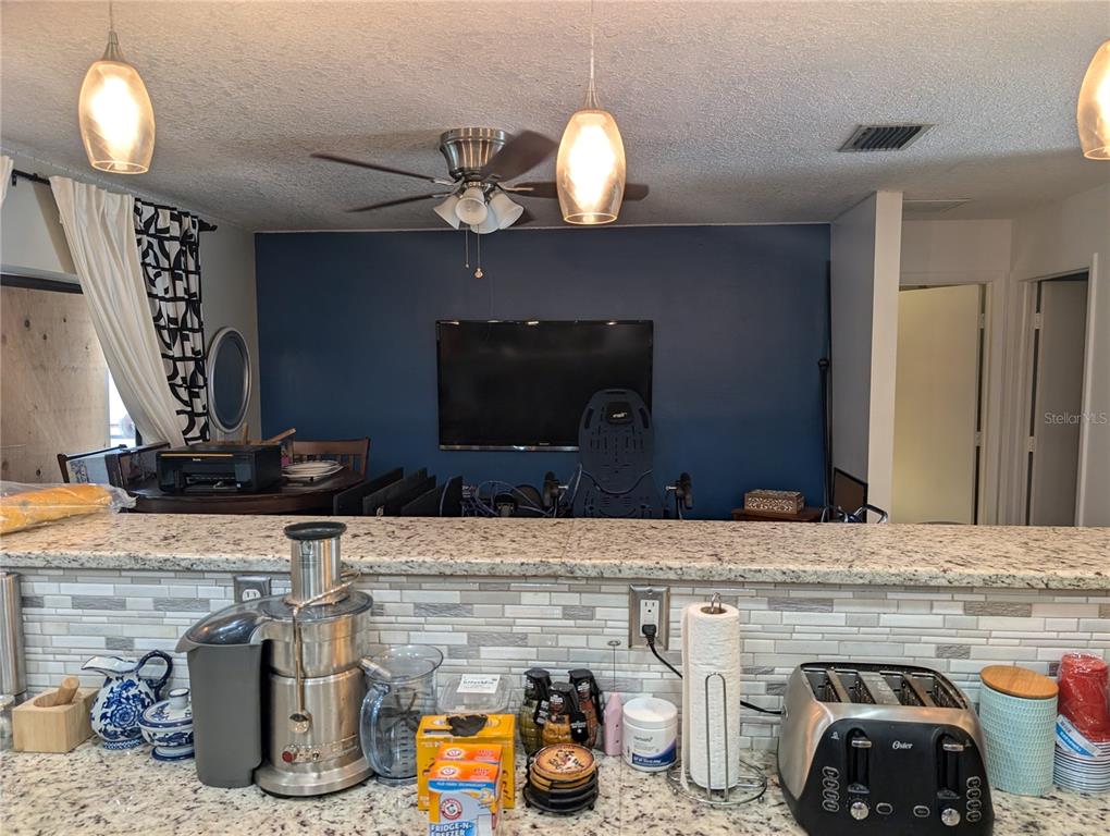 A kitchen with granite countertops and a tiled backsplash overlooks a dining area with blue walls — 4208 SUMMERDALE DRIVE, TAMPA, FL