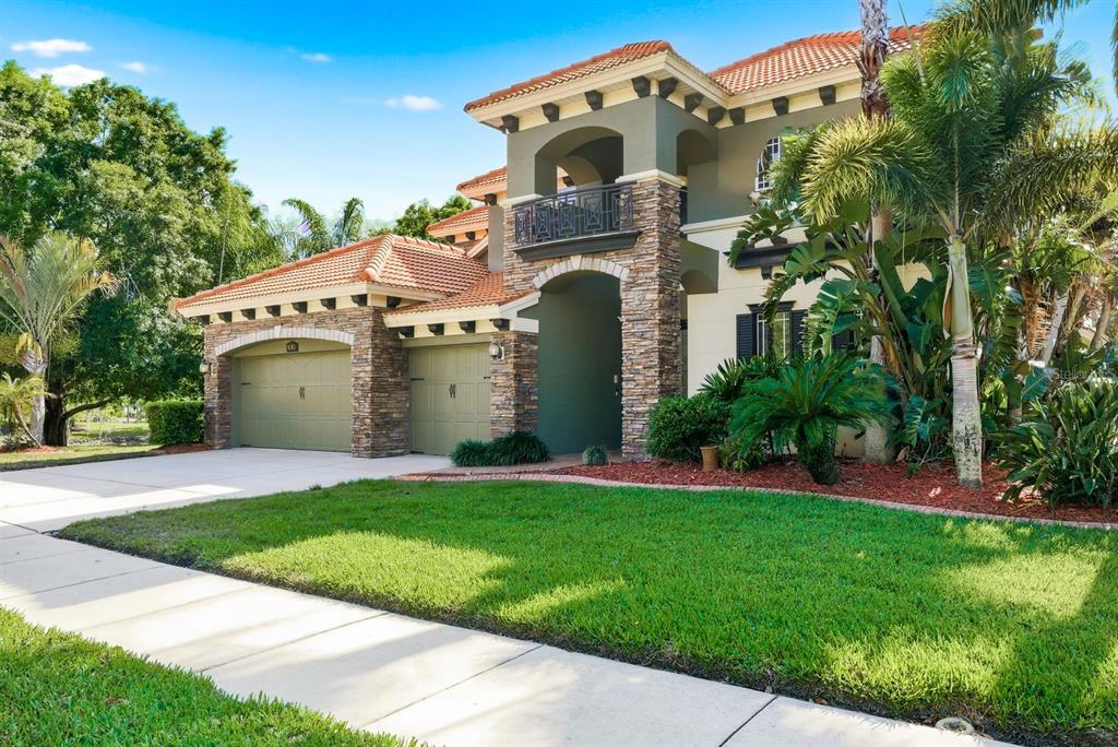 A two-story house with a stone-accented facade, tile roof, and a three-car garage — 9103 CREEDMOOR LANE, NEW PORT RICHEY, FL