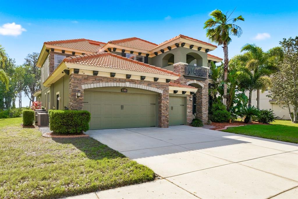 A two-story house with a tile roof, stone accents, and a three-car garage — 9103 CREEDMOOR LANE, NEW PORT RICHEY, FL