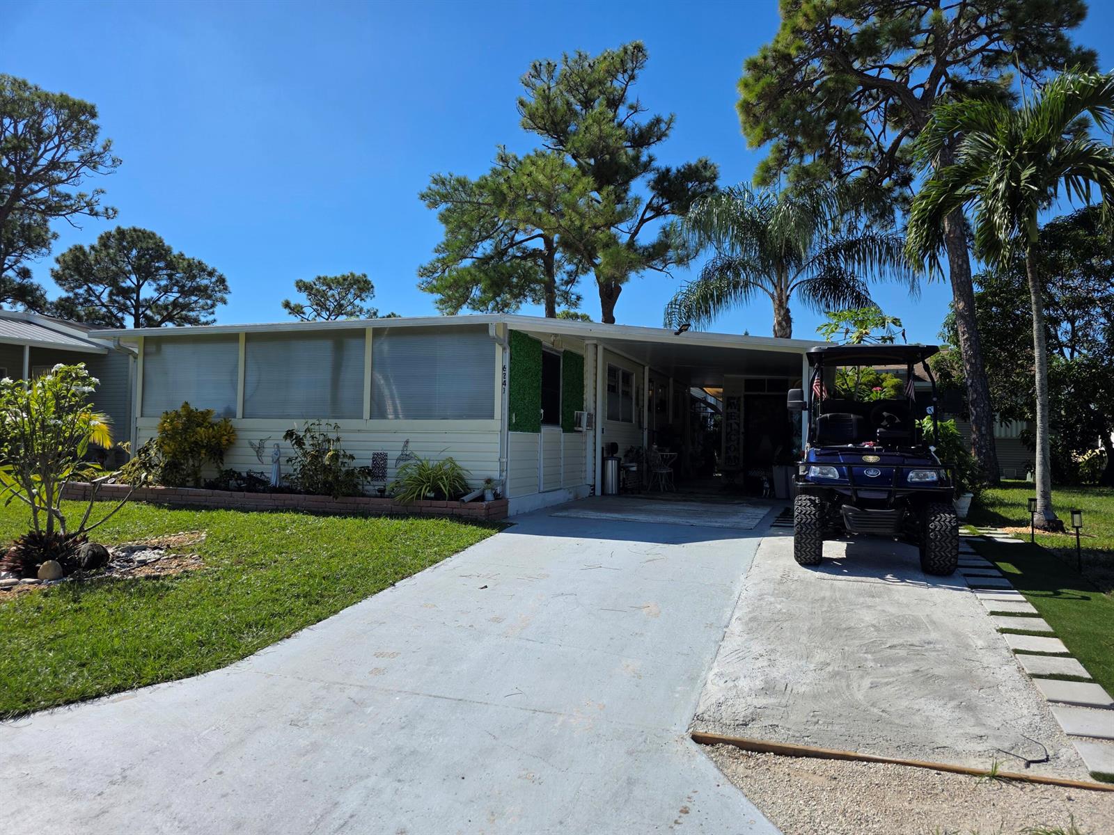 A single-story mobile home with a carport, a golf cart, and a landscaped front yard — 6241 Elm Lane, Lantana FL 33462, LANTANA, FL