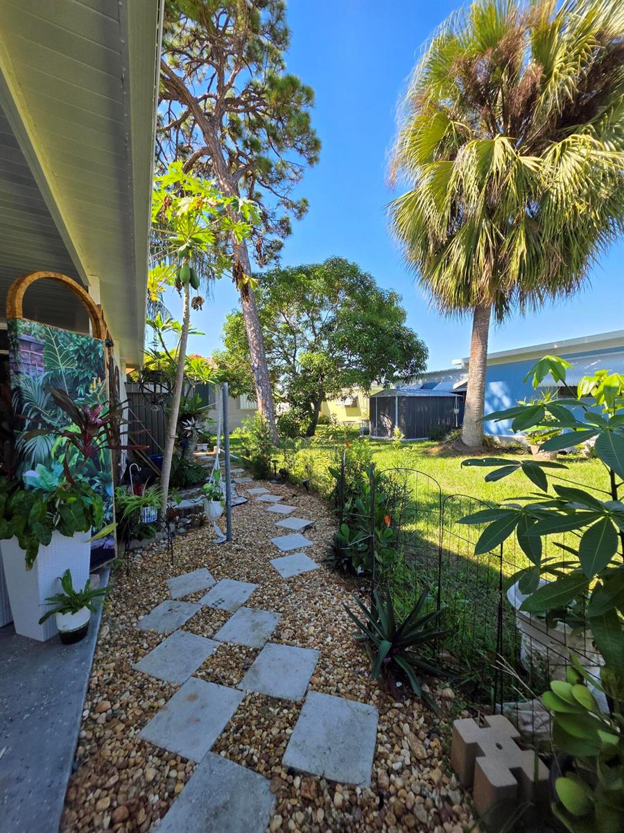 A backyard features a stone paver path, gravel ground cover, a palm tree, and landscaping — 6241 Elm Lane, Lantana FL 33462, LANTANA, FL