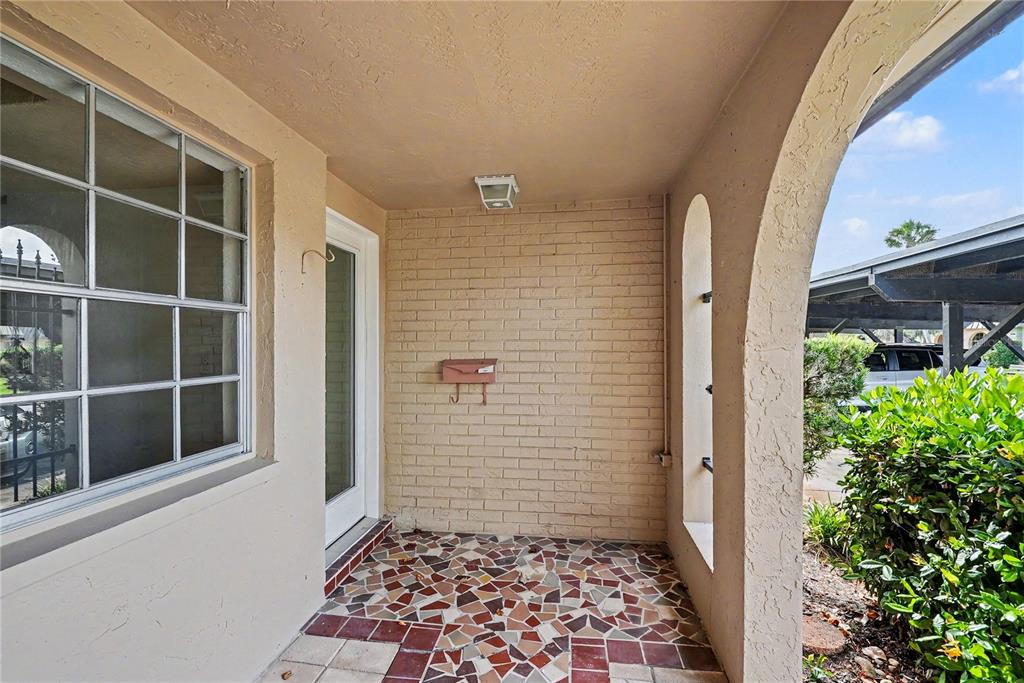 A covered porch features a brick wall, a mosaic tile floor, and an arched opening — 4135 STRATFORD DRIVE, NEW PORT RICHEY, FL