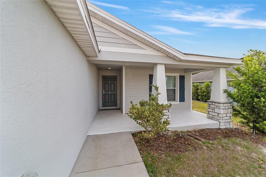 A concrete walkway leads to the covered front porch of a house with gray siding — 8941 SE 51ST, OCALA, FL