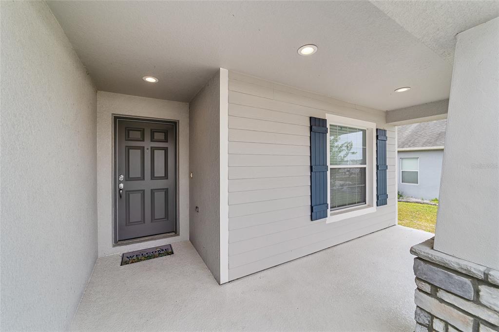 A covered front porch features a gray front door, light siding, and blue shutters — 8941 SE 51ST, OCALA, FL
