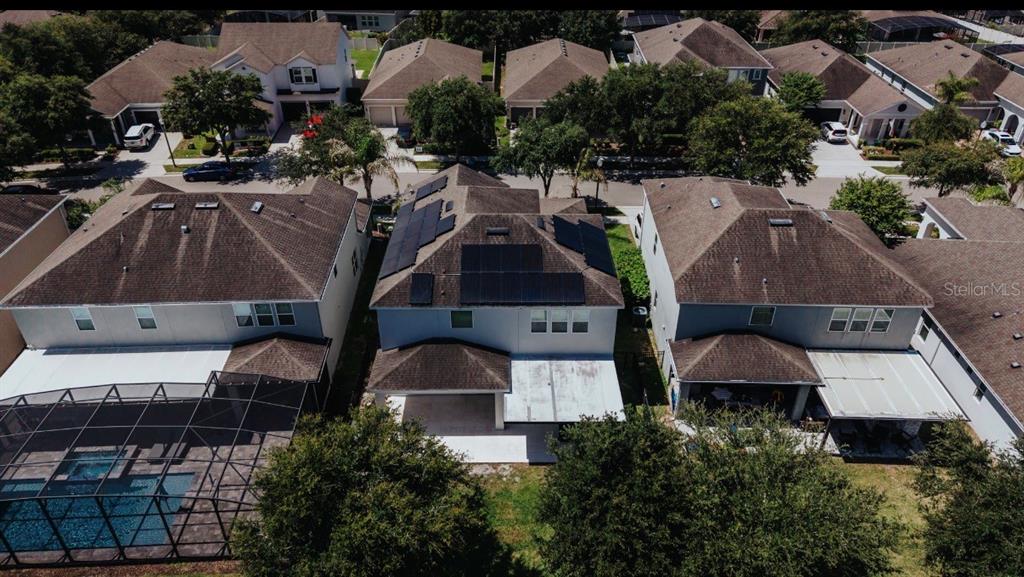An aerial view of three suburban houses, with the center home featuring rooftop solar panels — 5024 PALMETTO PARK DRIVE, WINTER GARDEN, FL