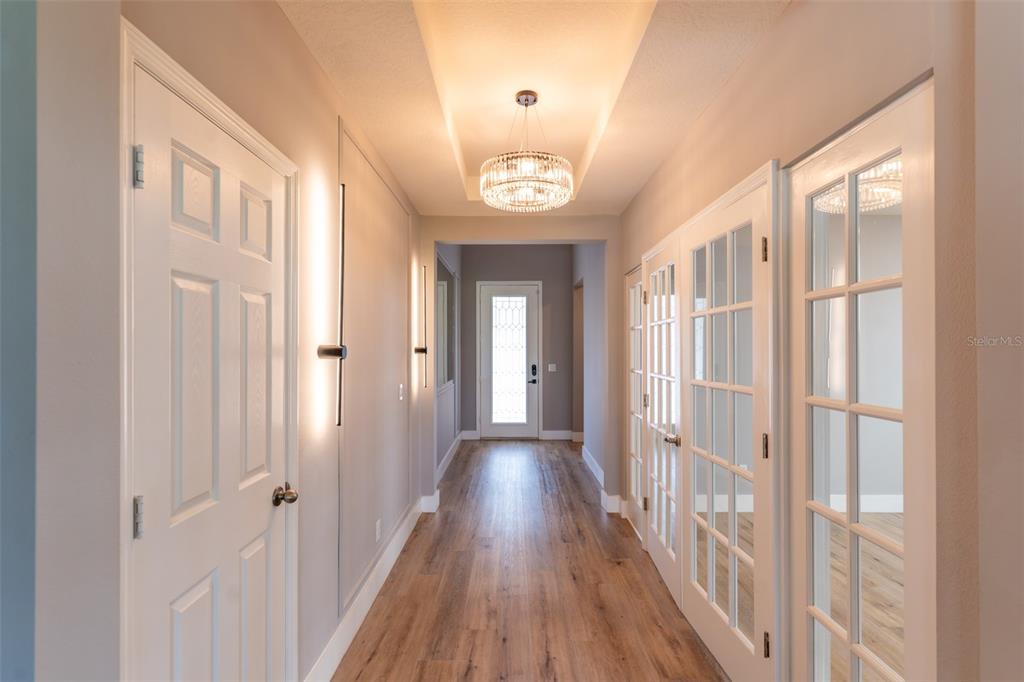 A hallway with wood-look flooring, a tray ceiling with a chandelier, and French doors — 5024 PALMETTO PARK DRIVE, WINTER GARDEN, FL