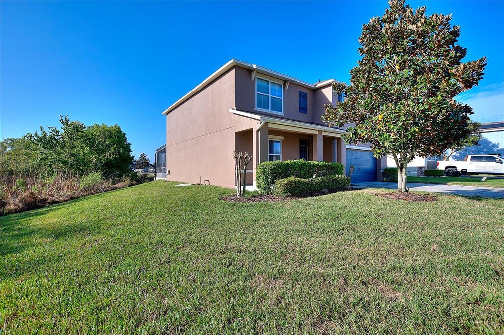 A two-story tan house with a garage and a large tree in the front yard — 519 OAKHURST WAY, LAKE ALFRED, FL