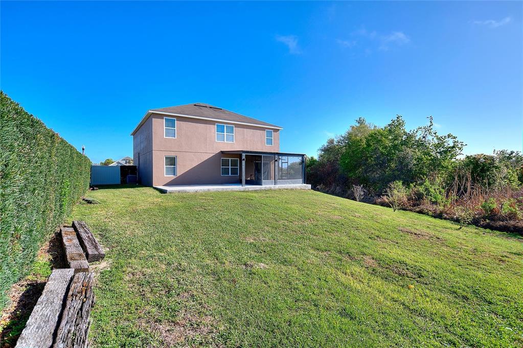 The rear exterior of a two-story house features a screened patio and a grassy yard — 519 OAKHURST WAY, LAKE ALFRED, FL