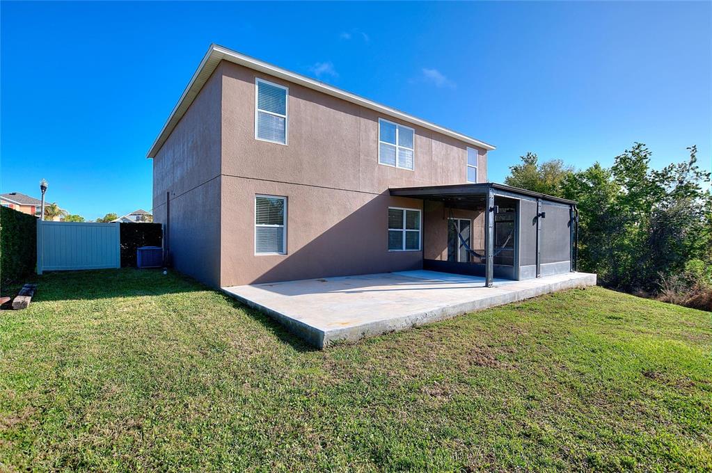 The back of a two-story house features a concrete patio and a screened-in porch — 519 OAKHURST WAY, LAKE ALFRED, FL