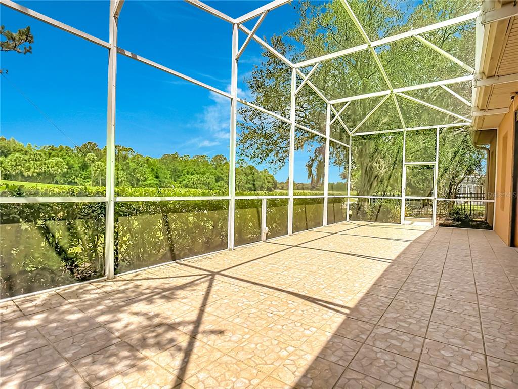 A screened-in patio with tiled flooring overlooks a grassy yard and trees — 294 ADDISON DRIVE, POINCIANA, FL