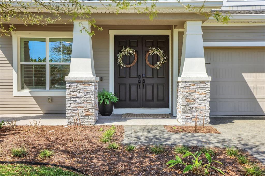 A two-story house with gray siding, stone accents, and a paved driveway under a blue sky — 6226 W FALLSGROVE LANE, PORT ORANGE, FL