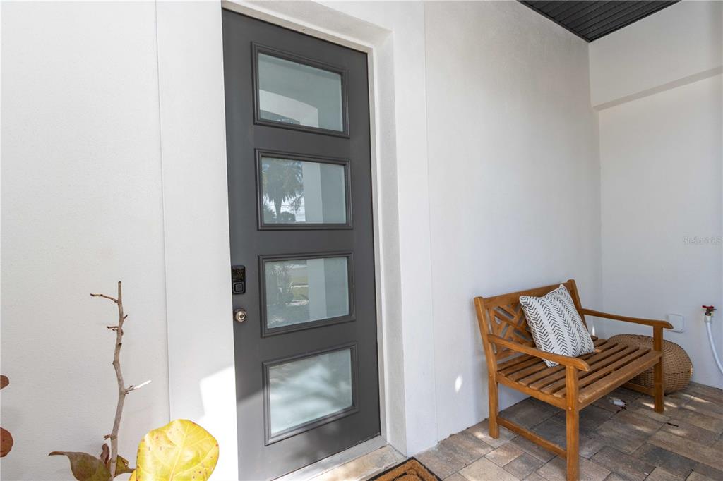 A gray front door with four glass panels sits next to a wooden bench — 430 PALM ISLAND SE, CLEARWATER BEACH, FL