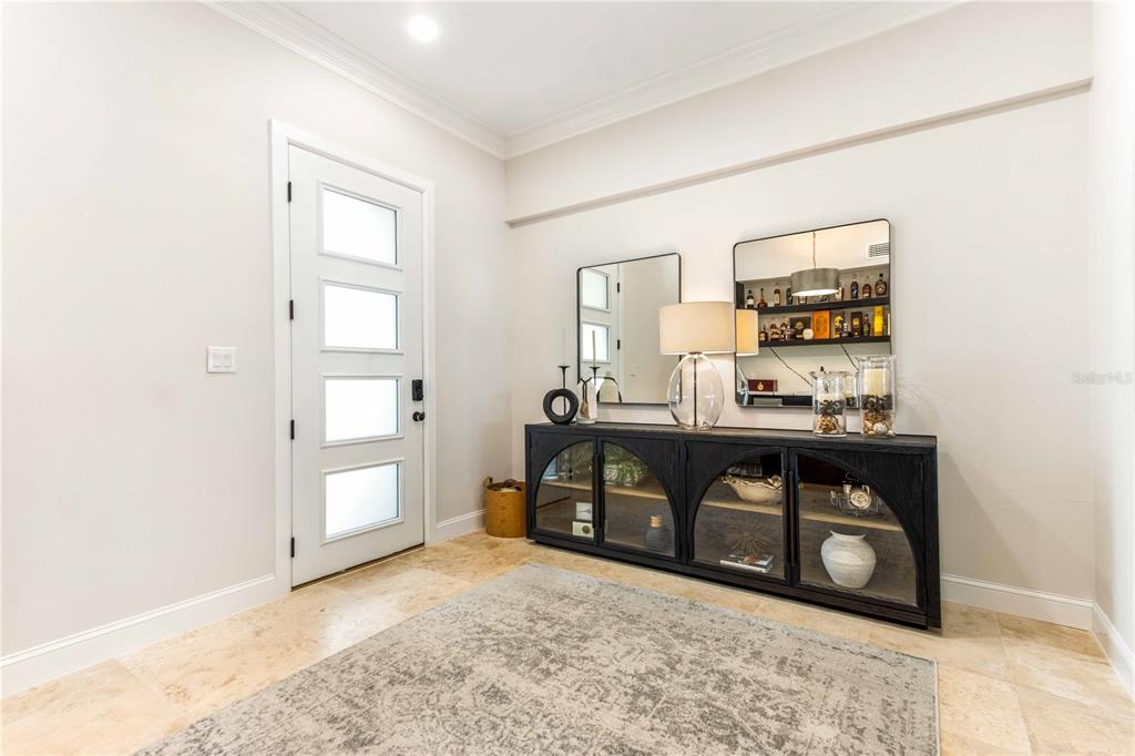 An entryway features a white door, a black arched cabinet, two mirrors, and stone flooring — 430 PALM ISLAND SE, CLEARWATER BEACH, FL