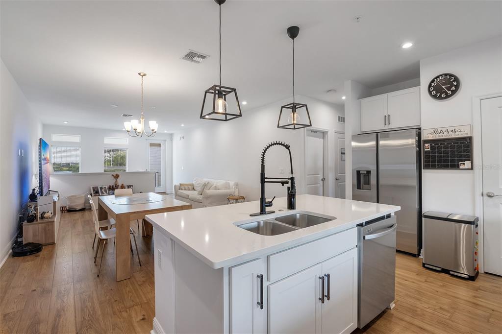 A modern kitchen with a white island and stainless steel appliances overlooks a dining area — 7251 NEMOURS PARKWAY, ORLANDO, FL