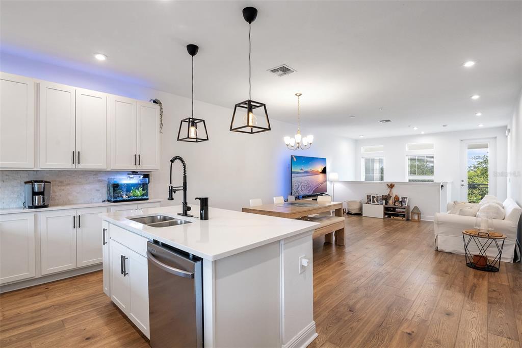 A modern open-concept kitchen with a white island, stainless steel appliances, and wood flooring — 7251 NEMOURS PARKWAY, ORLANDO, FL