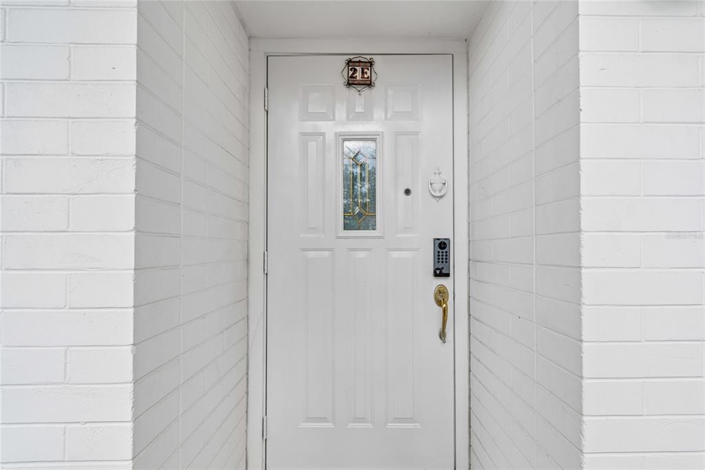A white front door with a small window and a keypad lock sits in a brick alcove — 1365 N SNELL ISLE BOULEVARD NE UNIT 2E, ST PETERSBURG, FL