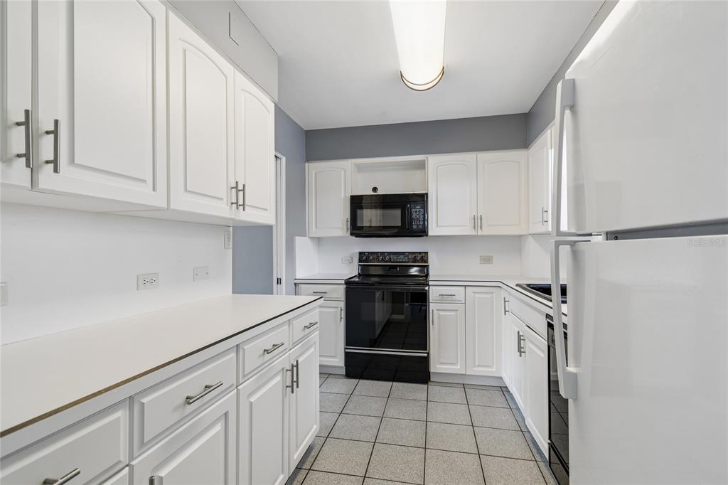 A kitchen with white cabinets, black appliances, gray walls, and gray tiled flooring — 1365 N SNELL ISLE BOULEVARD NE UNIT 2E, ST PETERSBURG, FL