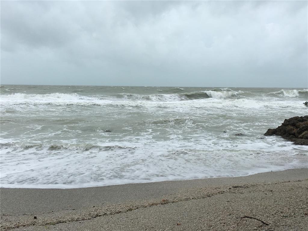 A view of a sandy beach with crashing waves under a cloudy, overcast sky — 7740 SANDERLING ROAD, SARASOTA, FL