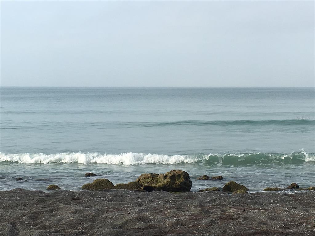 A view of the ocean with waves breaking over rocks on a sandy beach — 7740 SANDERLING ROAD, SARASOTA, FL