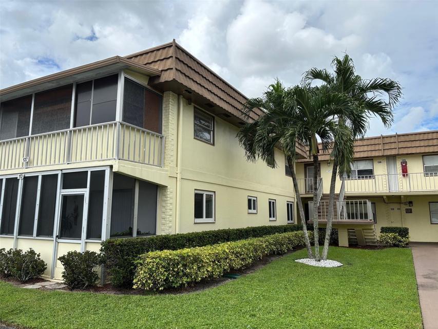 A two-story apartment building with yellow exterior walls, screened balconies, and a palm tree — 137 Saxony C Terrace, Delray Beach FL 33446, DELRAY BEACH, FL
