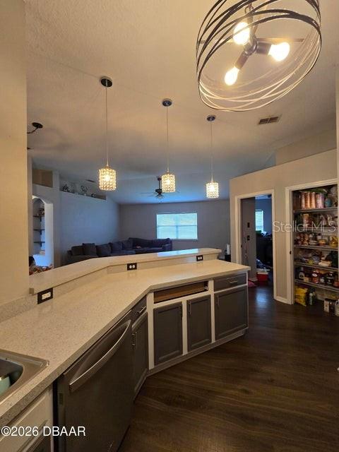 A kitchen features a breakfast bar, gray cabinets, pendant lighting, and dark wood-look flooring — 1409 SUTTON ISLAND DRIVE, DELAND, FL