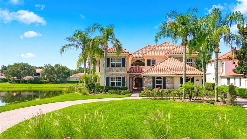 A two-story house with a tile roof and palm trees sits beside a lake — 6417 LAKE BURDEN VIEW DRIVE, WINDERMERE, FL