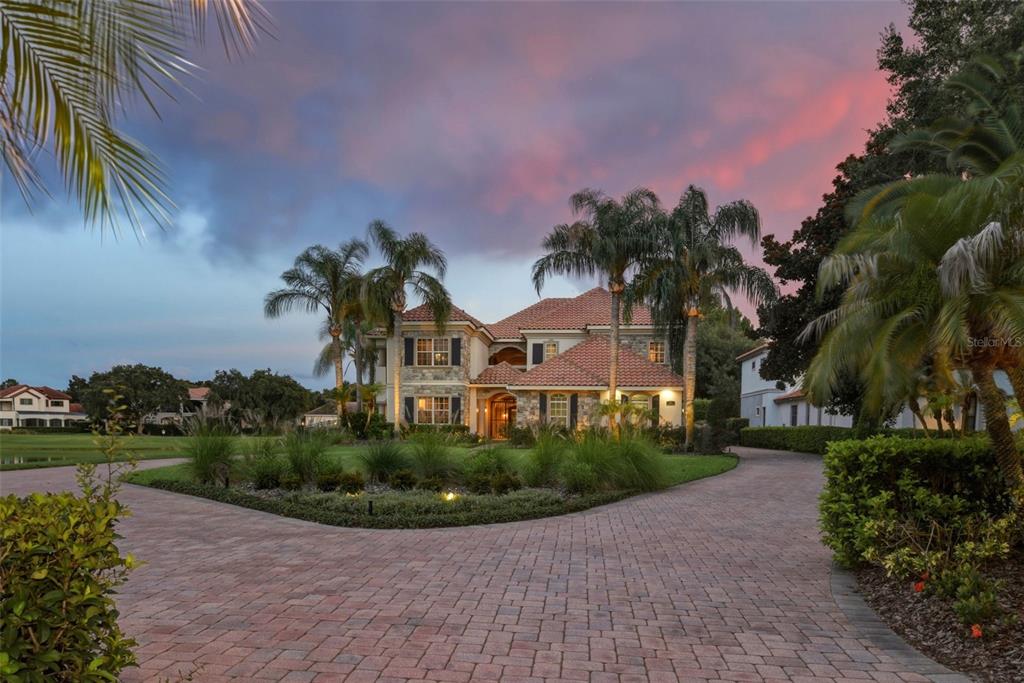 A two-story stone house with a tile roof sits behind a circular brick driveway — 6417 LAKE BURDEN VIEW DRIVE, WINDERMERE, FL