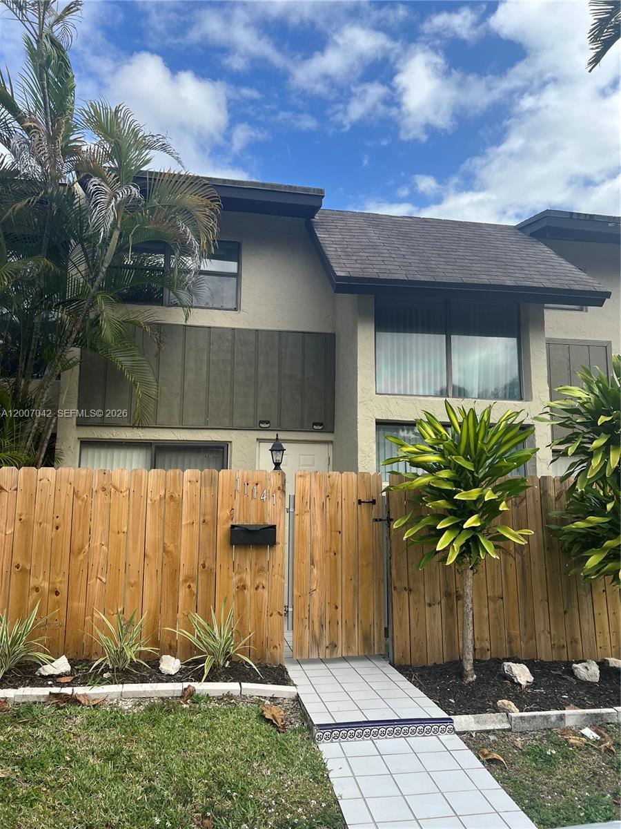 A two-story townhouse exterior features a wooden fence, a tiled walkway, and palm trees — 11141 SW 70th Ter, Miami FL 33173, MIAMI, FL
