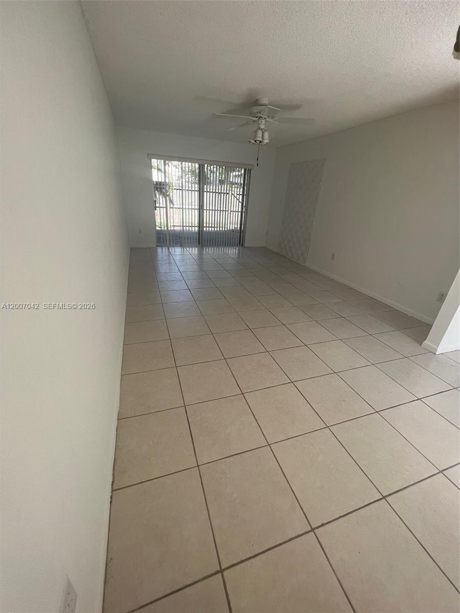 An empty room features light-colored floor tiles, white walls, and a sliding glass door — 11141 SW 70th Ter, Miami FL 33173, MIAMI, FL