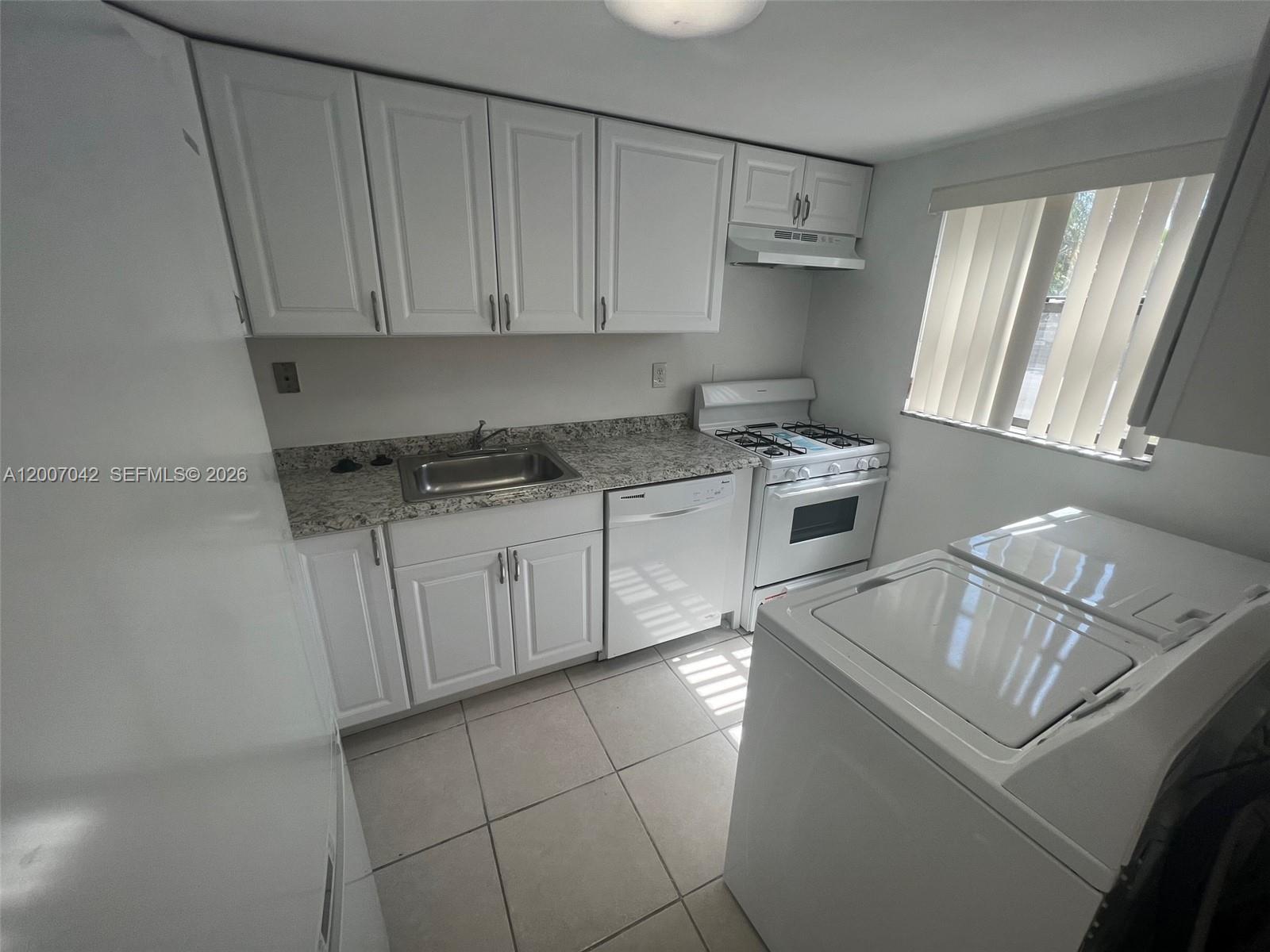 A kitchen features white cabinets, granite countertops, a gas stove, and a laundry appliance — 11141 SW 70th Ter, Miami FL 33173, MIAMI, FL