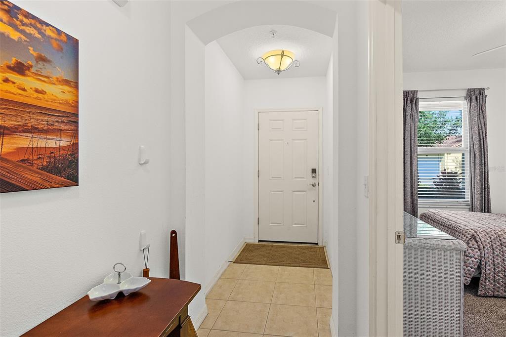 A tiled entryway features a white front door, a ceiling light, and an adjacent bedroom — 1300 CANOPY WALK LANE UNIT 1314, PALM COAST, FL