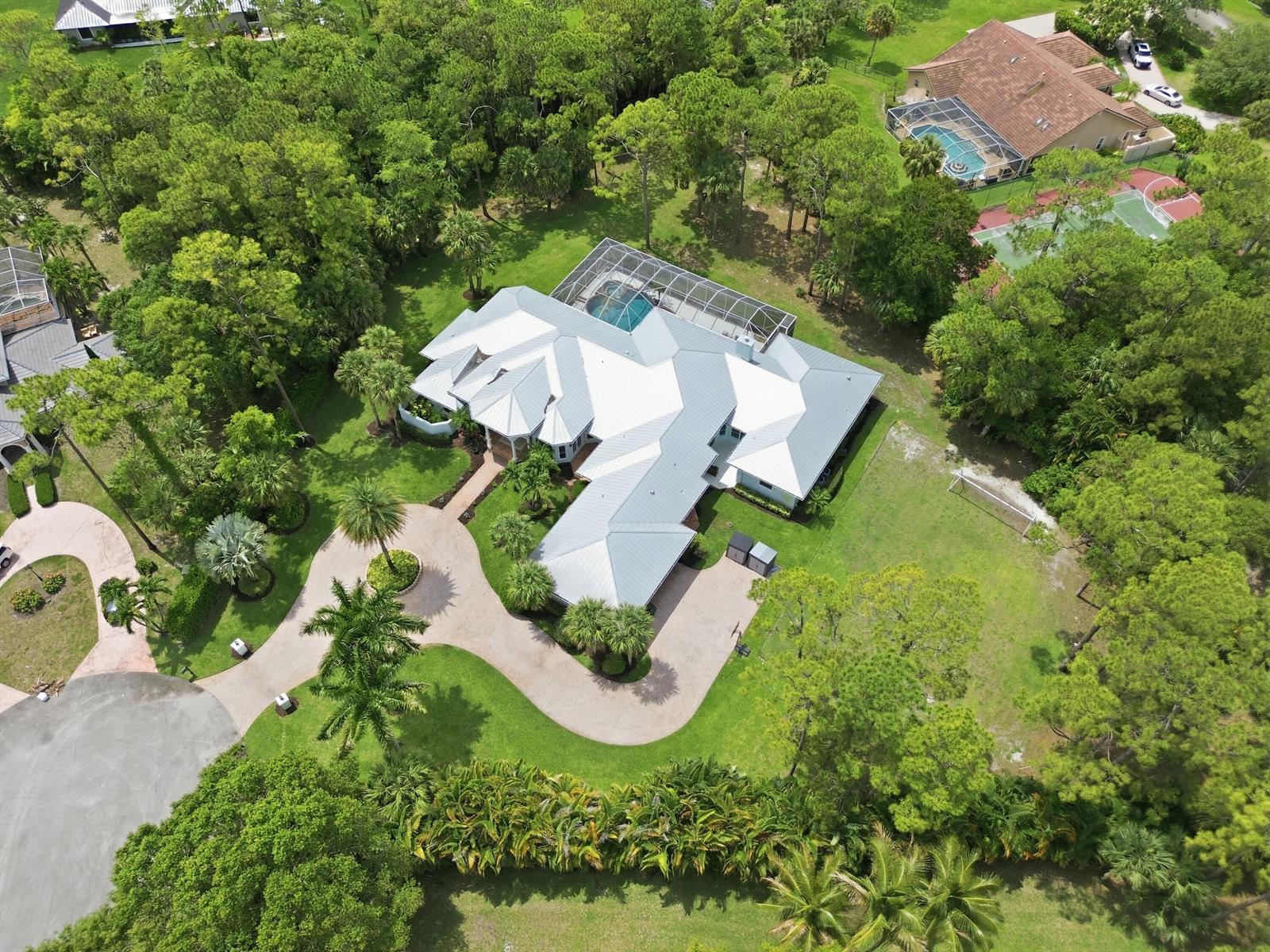 An aerial view shows a large house with a metal roof and screened pool area — 14737 Morgan Close, Wellington FL 33414, WELLINGTON, FL