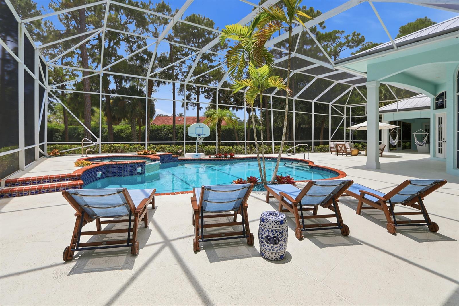 A screened-in pool area features lounge chairs, a hot tub, and a basketball hoop — 14737 Morgan Close, Wellington FL 33414, WELLINGTON, FL