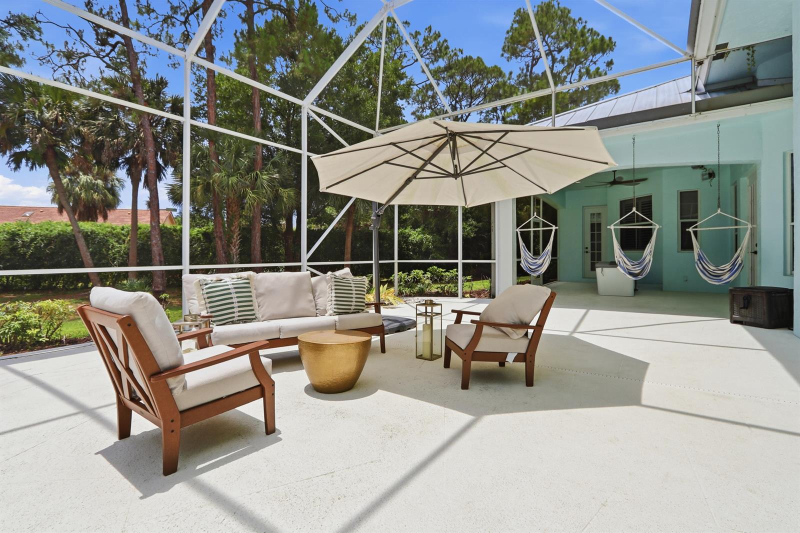 A screened-in patio features outdoor furniture, a large umbrella, and three hanging hammock chairs — 14737 Morgan Close, Wellington FL 33414, WELLINGTON, FL