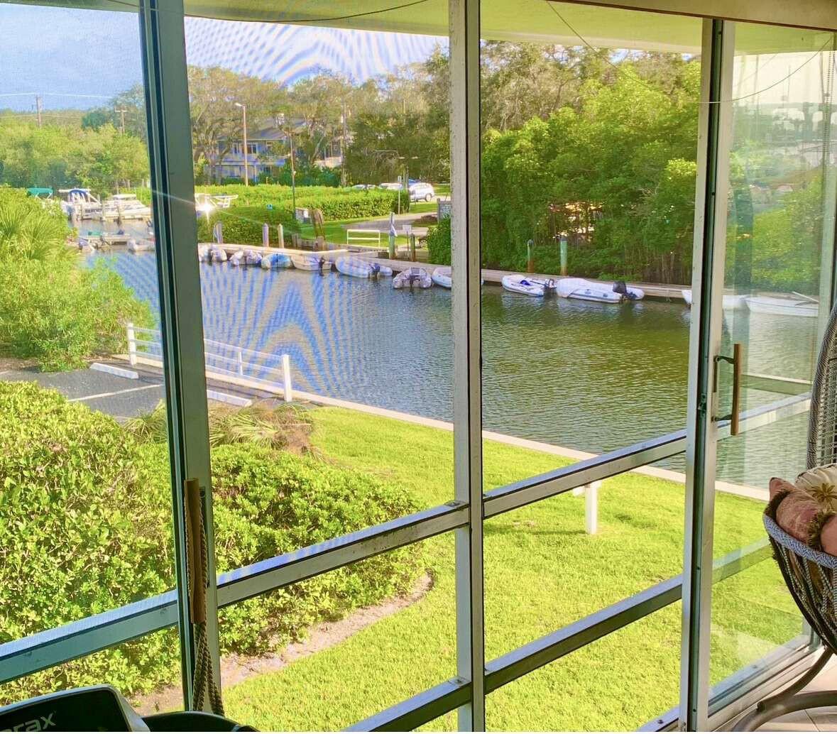 View from a screened porch overlooking a canal with docked boats and green landscaping — 200 Greytwig Road # 213, Vero Beach FL 32963, VERO BEACH, FL