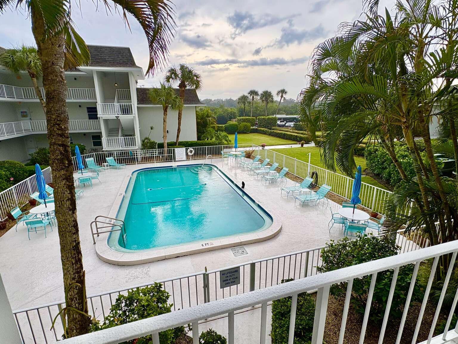 An elevated view of a rectangular swimming pool surrounded by lounge chairs and palm trees — 200 Greytwig Road # 213, Vero Beach FL 32963, VERO BEACH, FL