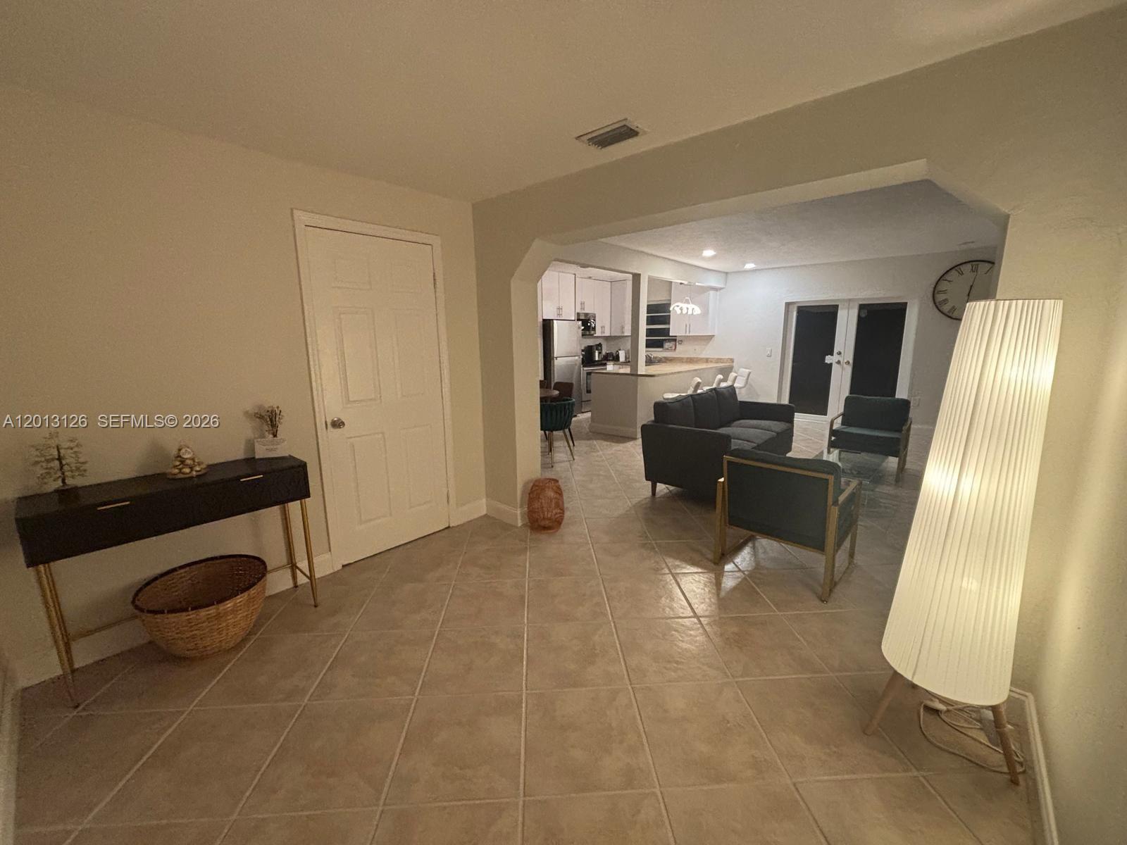 A tiled entryway leads into an open-concept living room and kitchen with white cabinetry — 1931 Mayo St, Hollywood FL 33020, HOLLYWOOD, FL