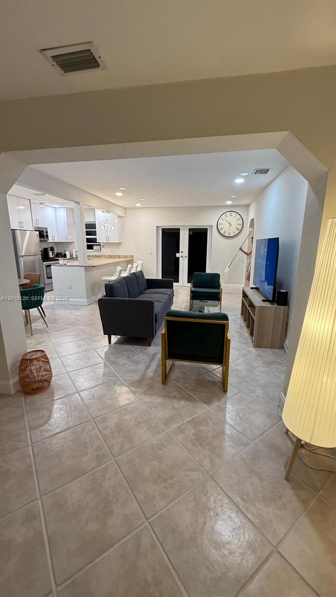An open-concept living room and kitchen feature tile flooring, a grey sofa, and modern furniture — 1931 Mayo St, Hollywood FL 33020, HOLLYWOOD, FL